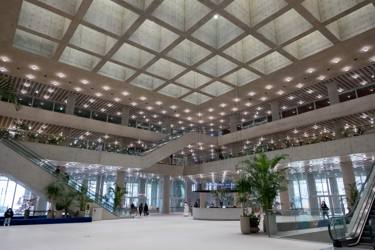 The ground-floor public atrium of LG Arts Centre Seoul, featuring Tadao Ando’s characteristic board-formed concrete coffered ceiling above a multi-level lobby connecting the Park Gate entrance to the venue’s cultural and retail spaces (Photo: iStock)