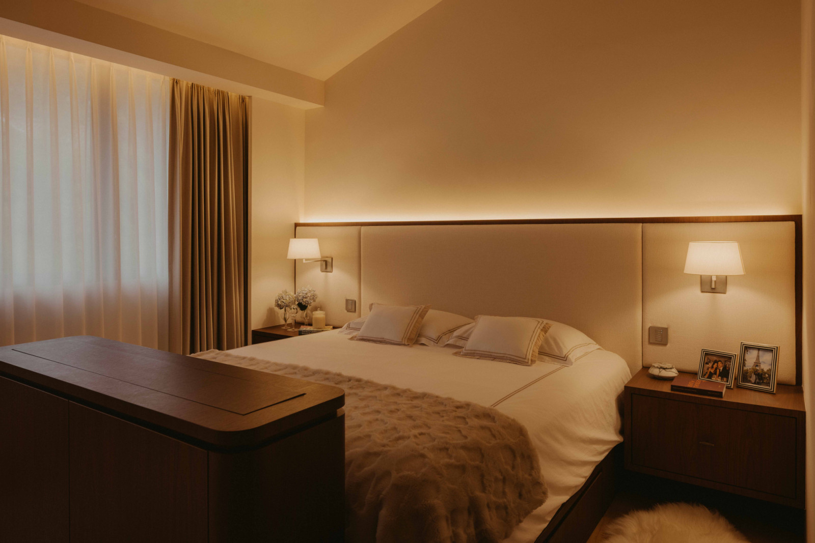 The master bedroom matches timber laminate for the carpentry with a fabric headboard and engineered timber floors