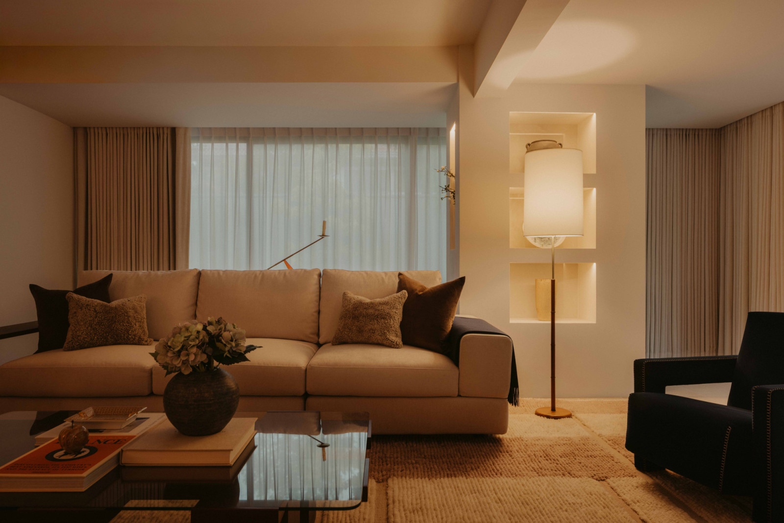 The living room is anchored by a generous sofa and layered textiles, with full-height curtains filtering daylight