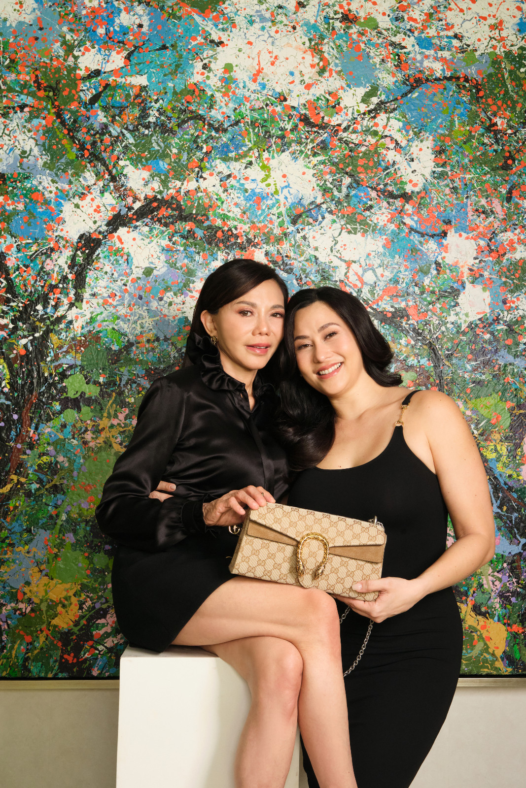 Dr Vicki Belo and Cristalle Belo-Pitt smiling tenderly, wearing black, sleek Gucci outfits