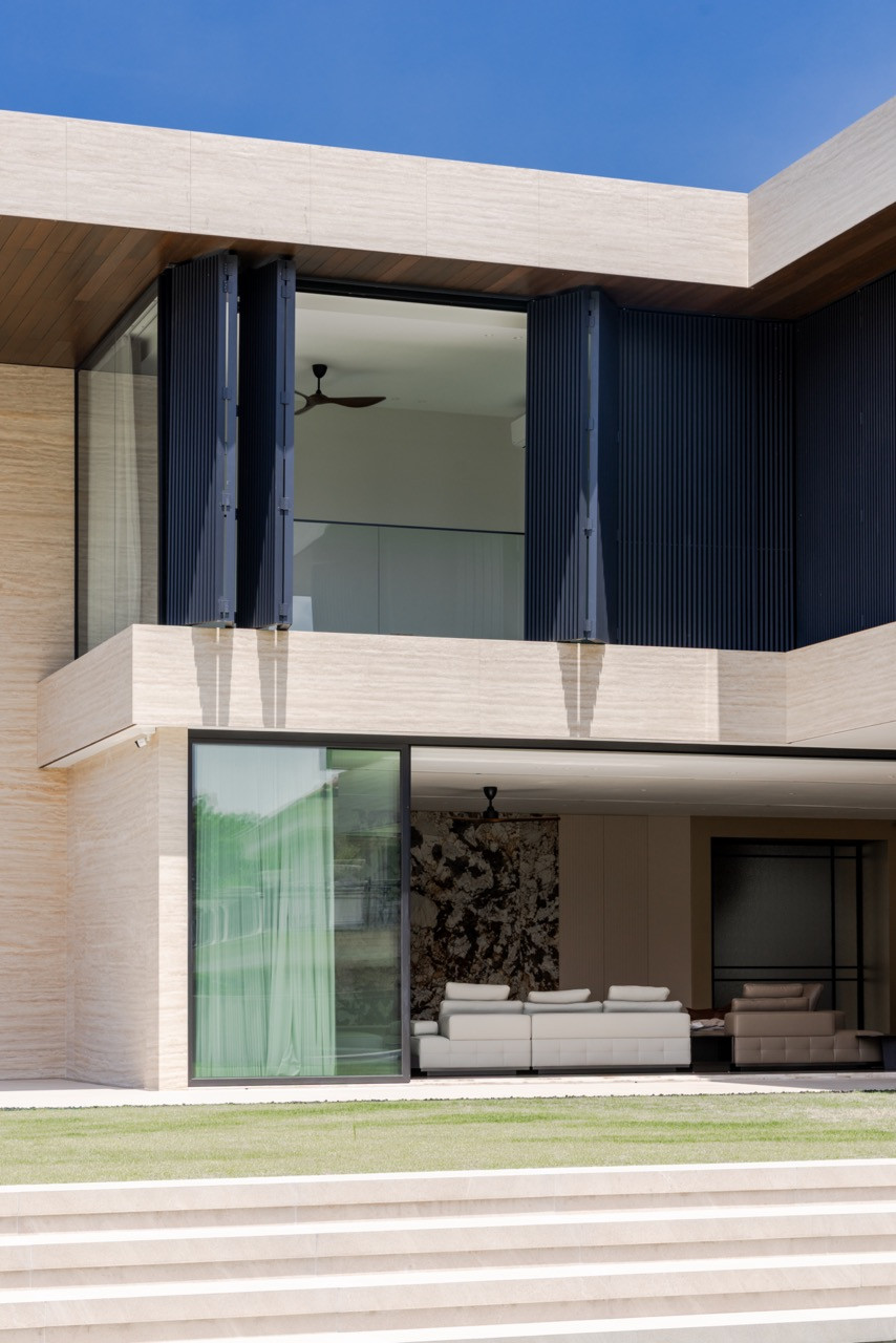 The rear elevation from the basketball court, showing the L-shaped plan with the living and dining areas opening fully onto the stepped terrace
