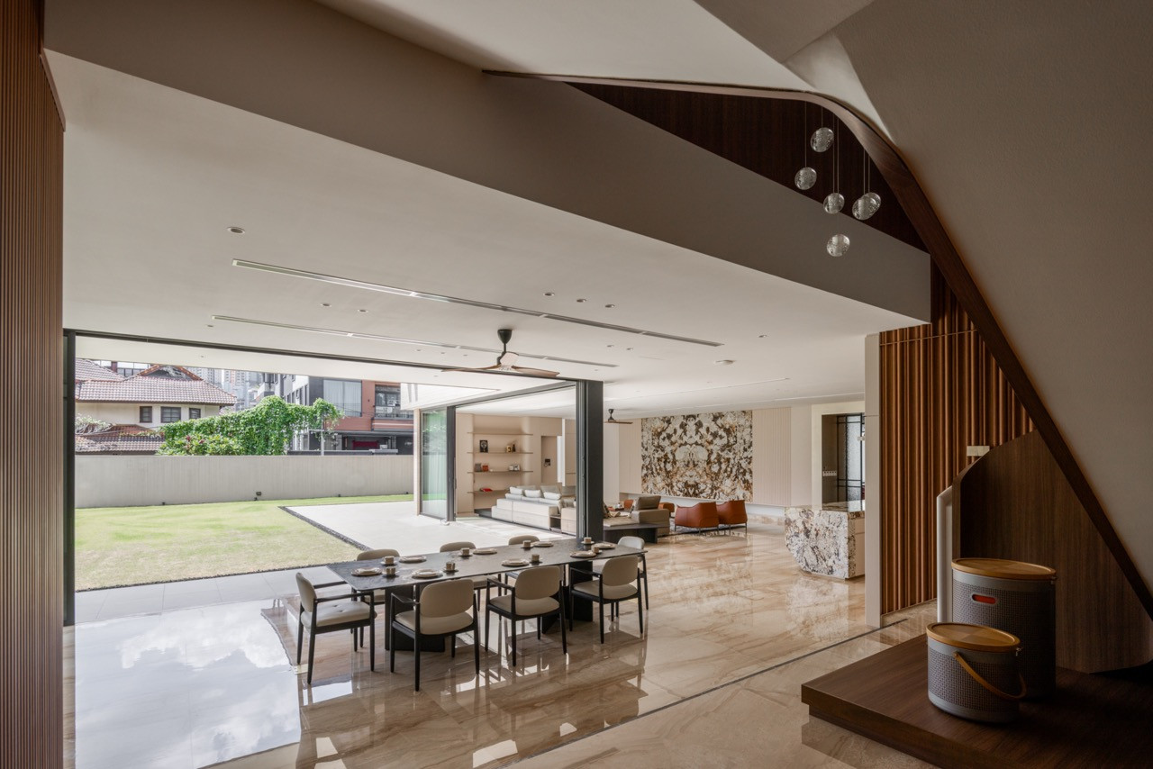 The ground floor plan seen from the staircase side, showing the dining area, living room, feature marble wall, and the lawn through the full-height sliding glass doors