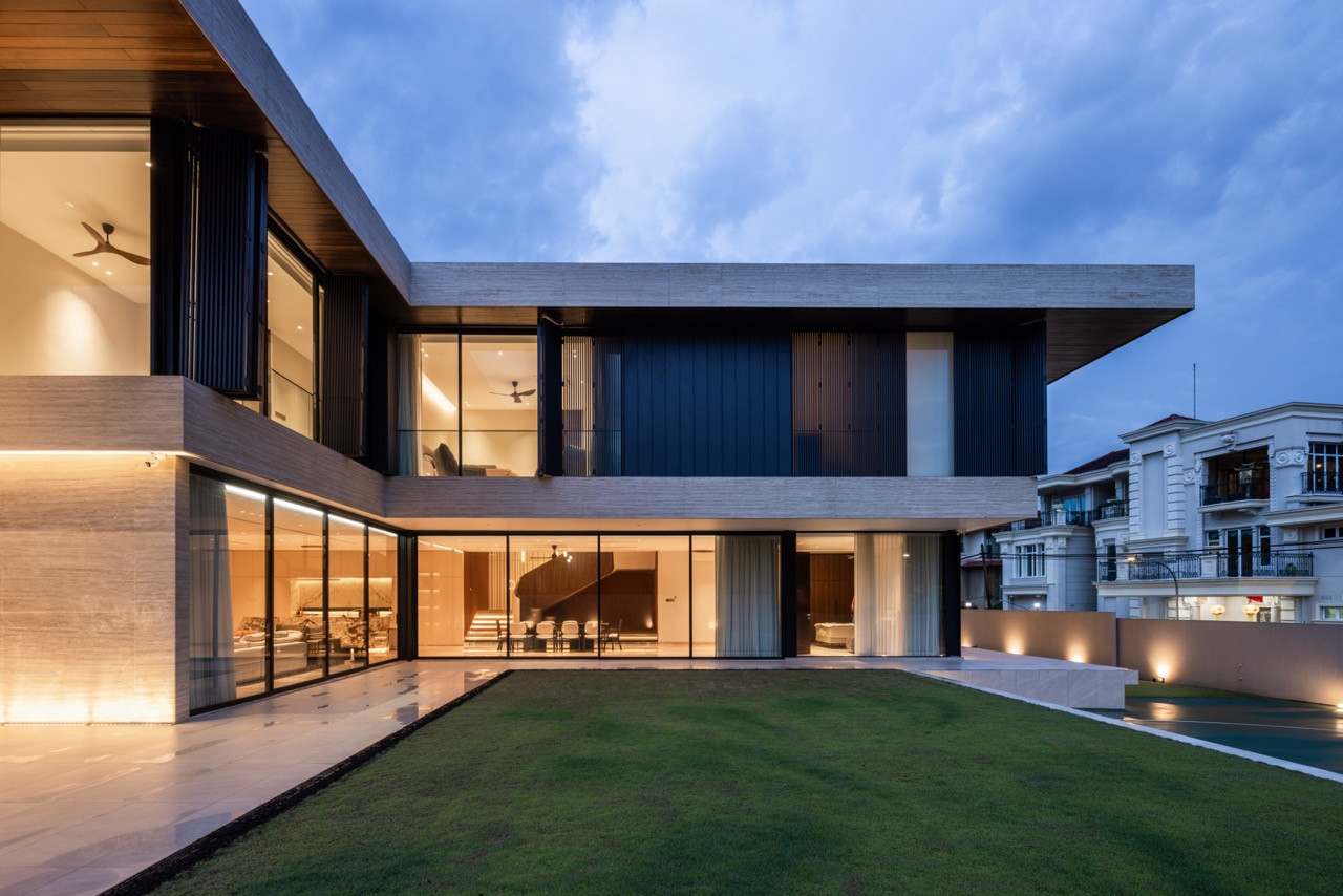 The full lawn-facing elevation showing both wings of the L-shaped plan, with the bronze spiral staircase visible through the ground-floor glazing