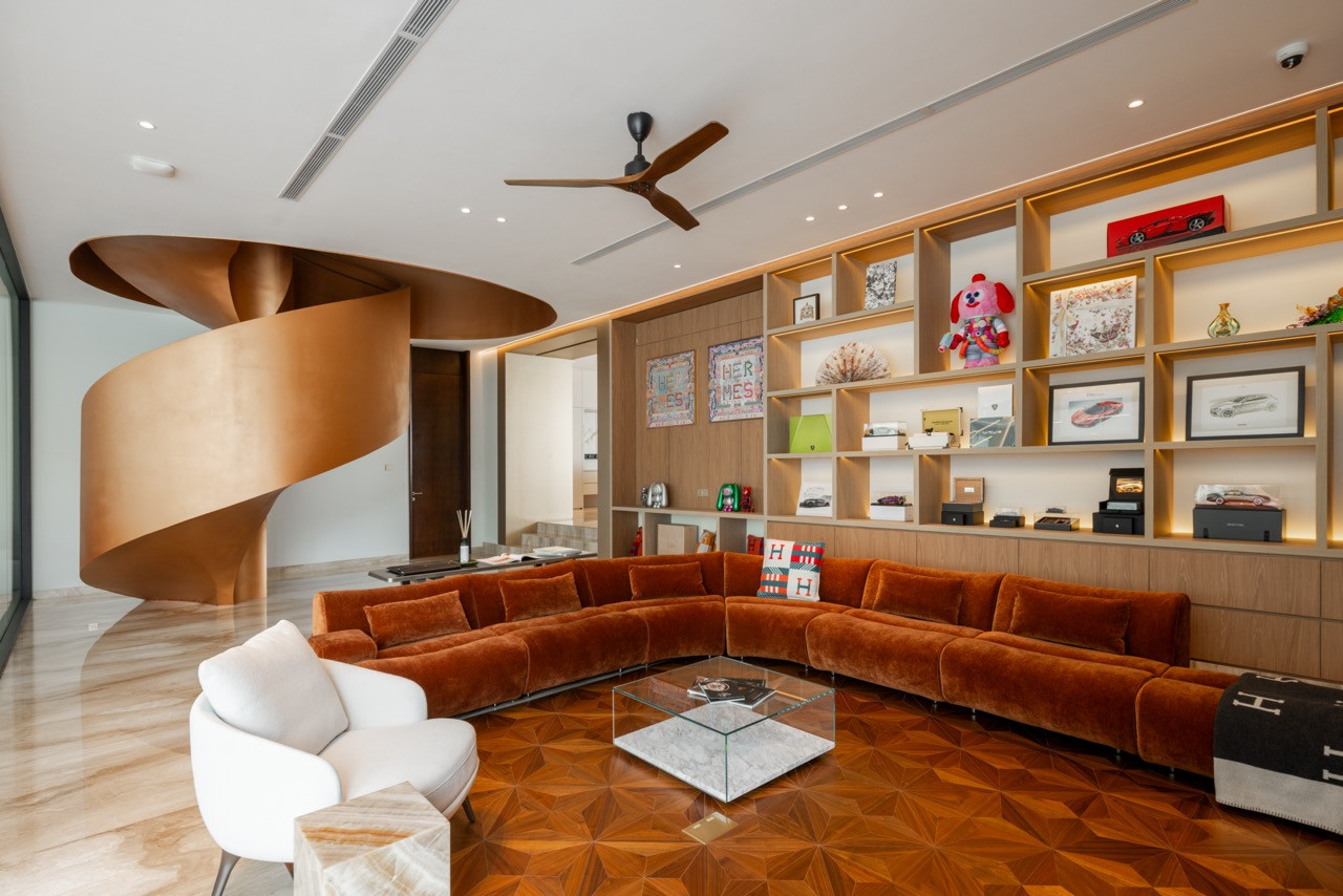 The car lounge showing the bronze spiral staircase, curved velvet sofa, display shelving, and parquet flooring