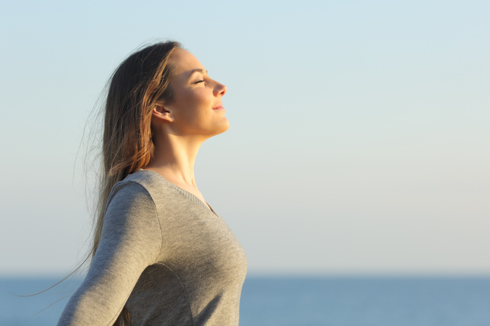 Side view portrait of a relaxed woman breathing fresh air on the beach