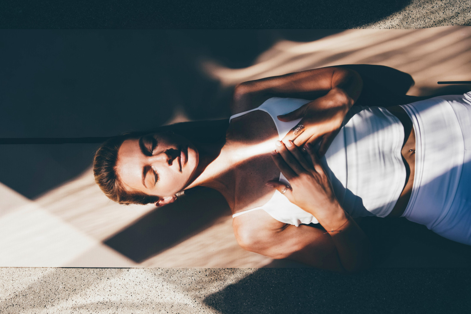 Graceful slim woman trainer in white sportswear practices yoga exercises on floor mat.