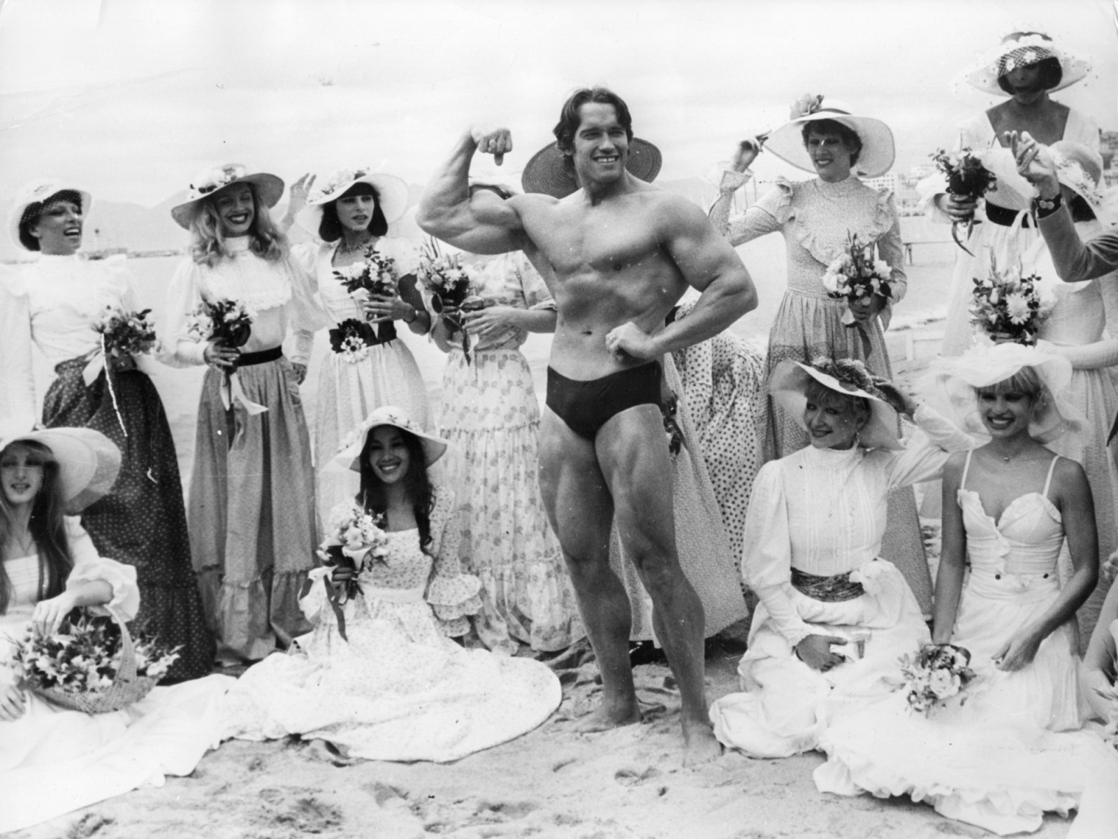 Arnold Schwarzenegger, who first became famous as ‘Mr Universe’, on Cannes beach during the 1977 Film Festival with the girls from the Folies Bergere (Photo: Keystone/Getty Images)