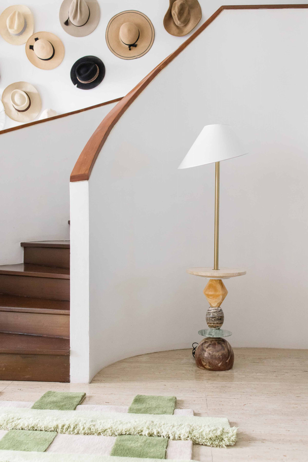 Stacked Sonata Lamp standing guard beside a curving staircase accented by a collection of hats