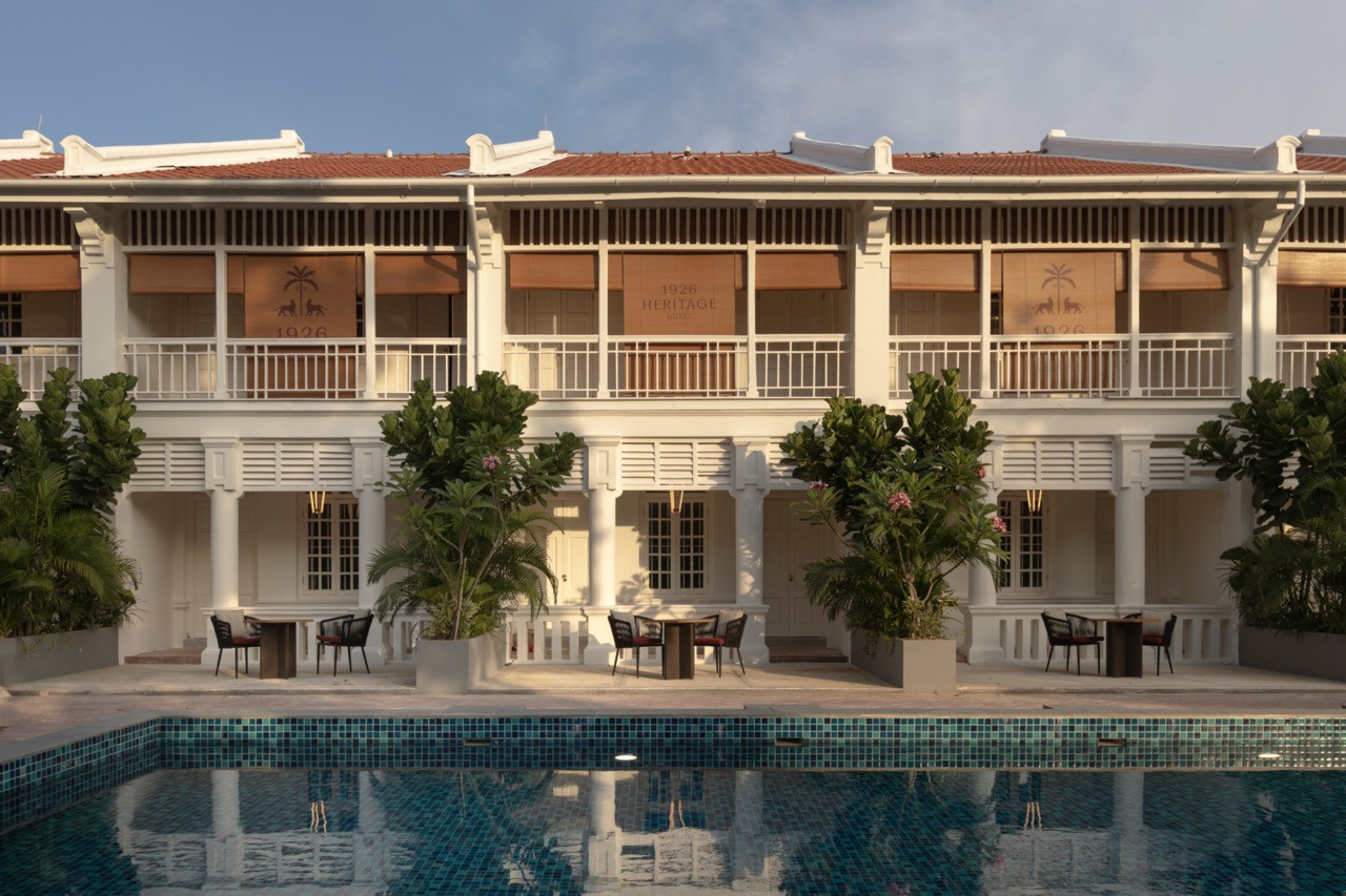 The pool-facing facade in late afternoon light, showing the hotel's palm and panther motif repeated across the louvred shutters of the upper floor