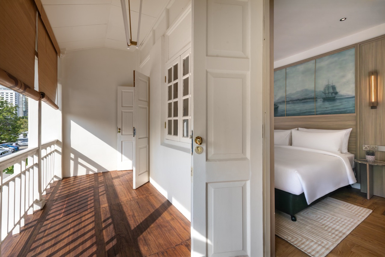 The original timber-floored verandah of a Colonial King room, with the panelled door and glazed fanlight opening into the bedroom beyond