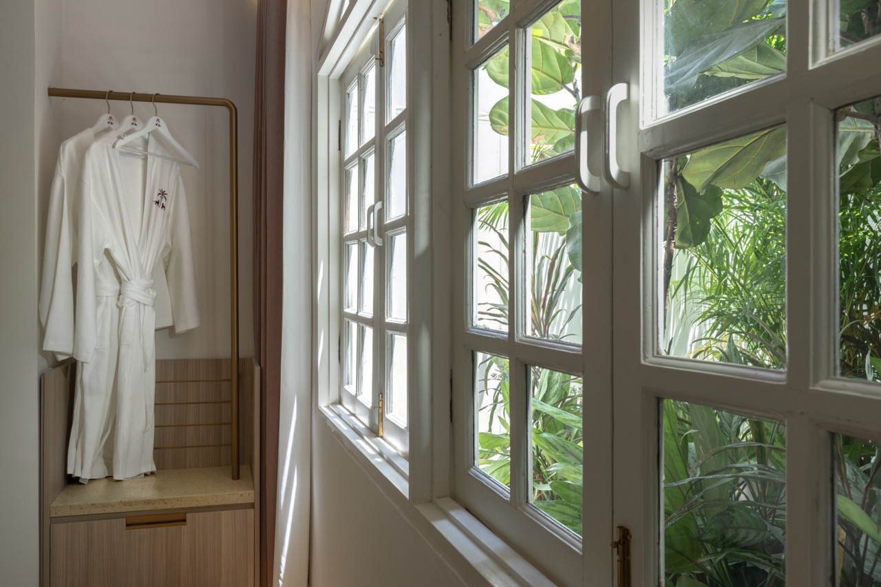 Original casement windows in the Residency Suite, with hotel robes on a brass rail alongside