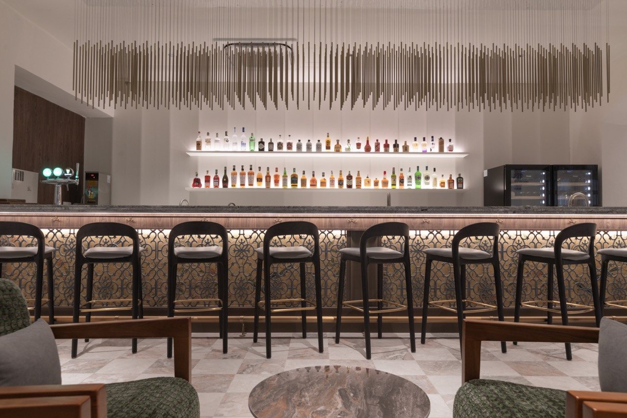 The U-Bar counter, showing the backlit spirit shelves, granite bar top and decorative wrought-iron bar front; the brass rod ceiling installation above