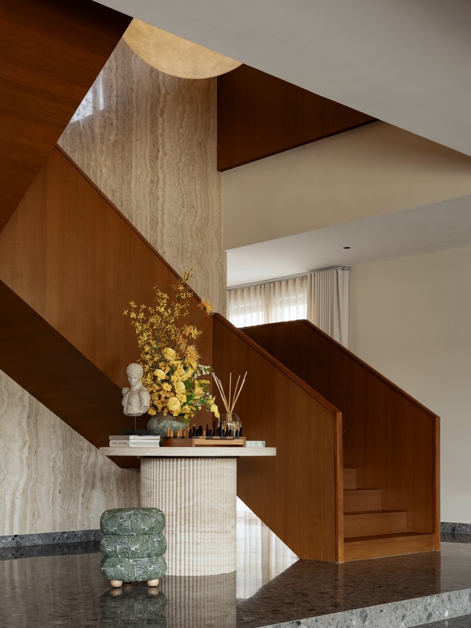 The ground floor staircase hall with travertine wall cladding and timber balustrade