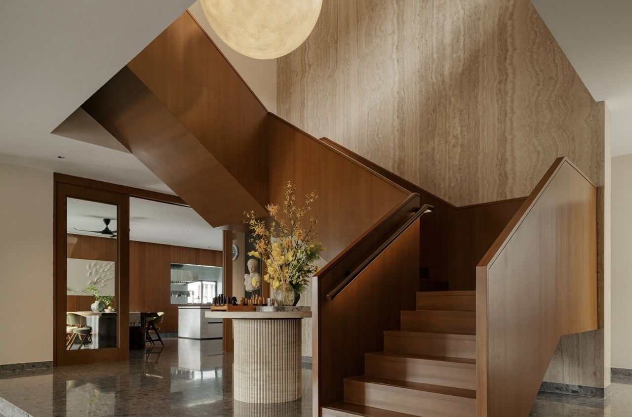 The ground floor staircase hall with angled timber soffit, travertine wall cladding and a fluted stone console table