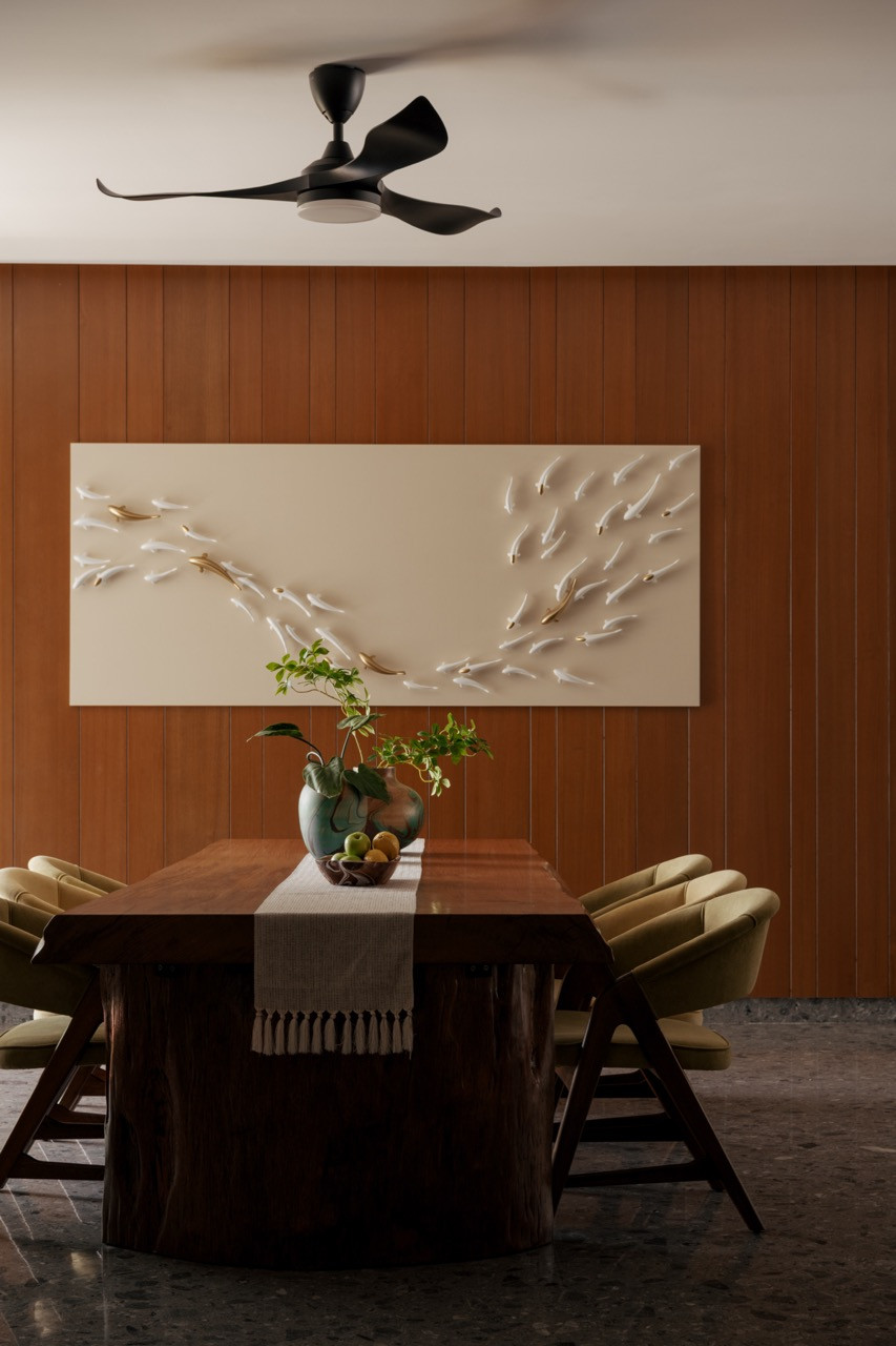 The family dining area with a solid timber table, olive-upholstered chairs and vertical timber wall panelling