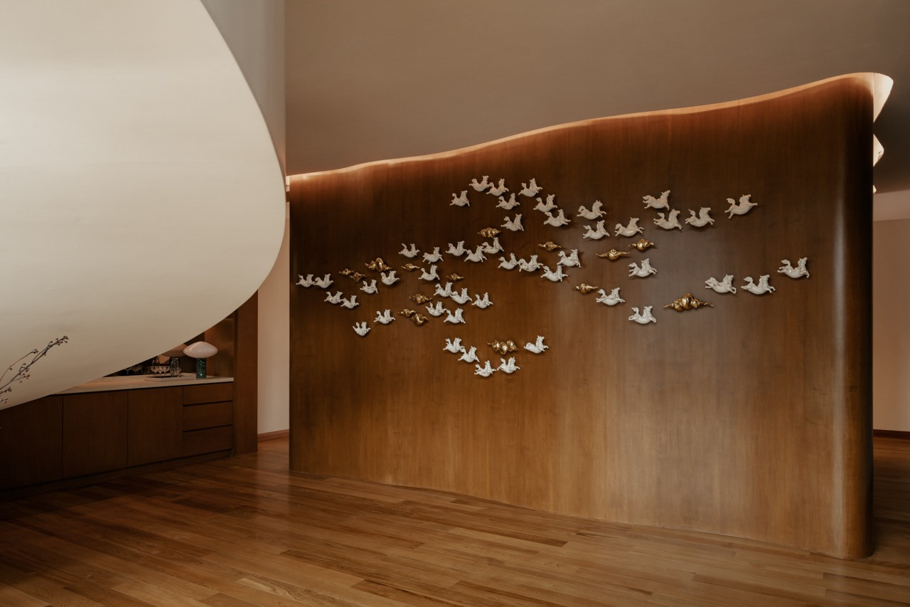 The curved timber accent wall of the entertainment lounge on the first floor, with a white and gold figurine installation