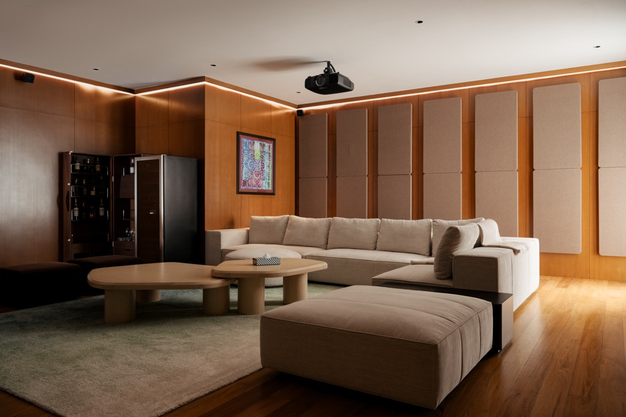 The entertainment lounge on the first floor, fitted with a ceiling-mounted projector, acoustic wall panels and a sectional sofa