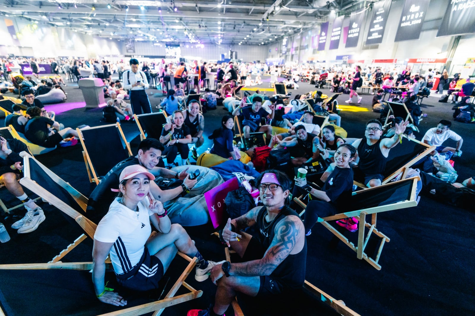 Wide shot of a massive, crowded hall at AsiaWorld-Expo filled with thousands of Hyrox participants and spectators in athletic gear under bright arena lighting.