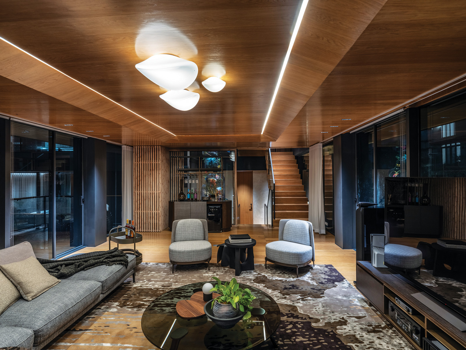 A bar awaits at the end of the living room as the wooden stairs beckon to explore the upper floors