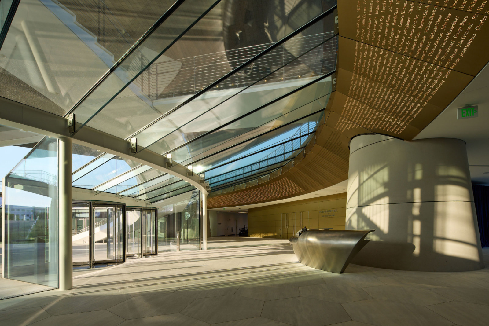 The museum's ground-level entrance lobby, its glazed ceiling admitting natural light alongside a curved interior wall bearing the names of Medal of Honor recipients in gilt lettering (Photo: Corey Gaffer)
