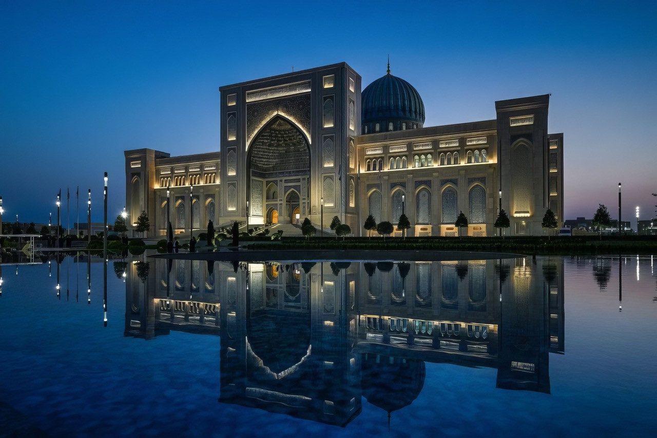 The Islamic Civilization Center in Tashkent at dusk, its monumental portal and turquoise dome reflected in the forecourt water feature