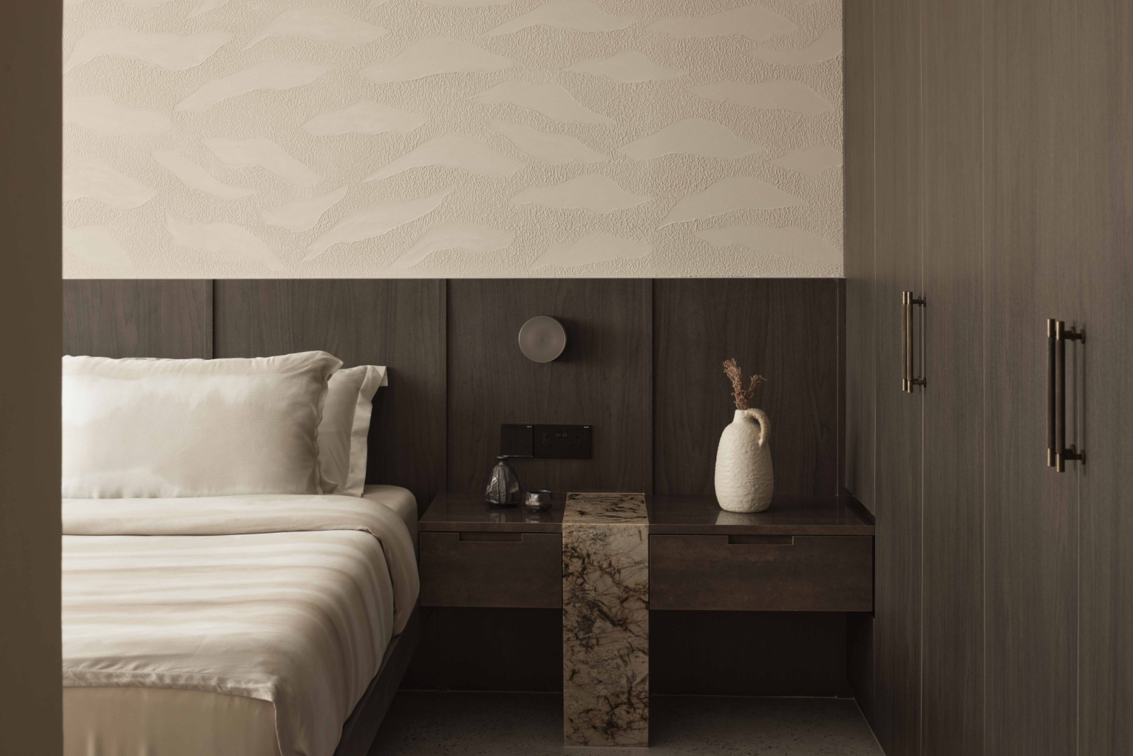 Dark wood tones, warm lighting and tactile finishes in the bedroom echo the stillness of an evening abroad