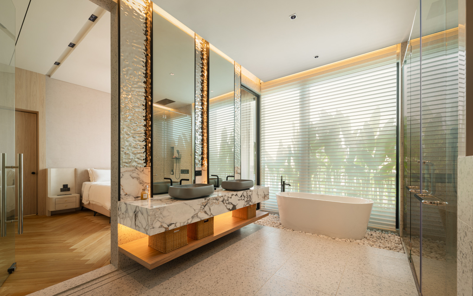 The upper floor master bathroom vanity with dual grey vessel sinks on a marble counter, wavy reflective tile panels flanking the full-height mirrors, and a white freestanding bathtub visible to the right