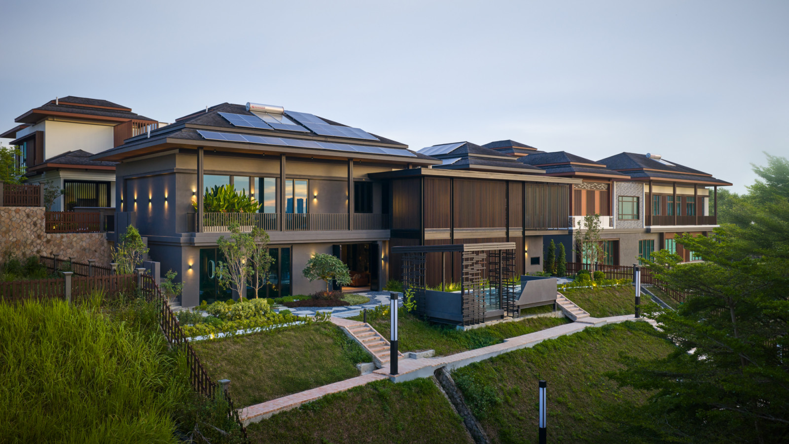 Daytime aerial showing the home's solar-panelled roof, vertical timber battens and terraced garden in the context of the wider Setia Eco Park estate