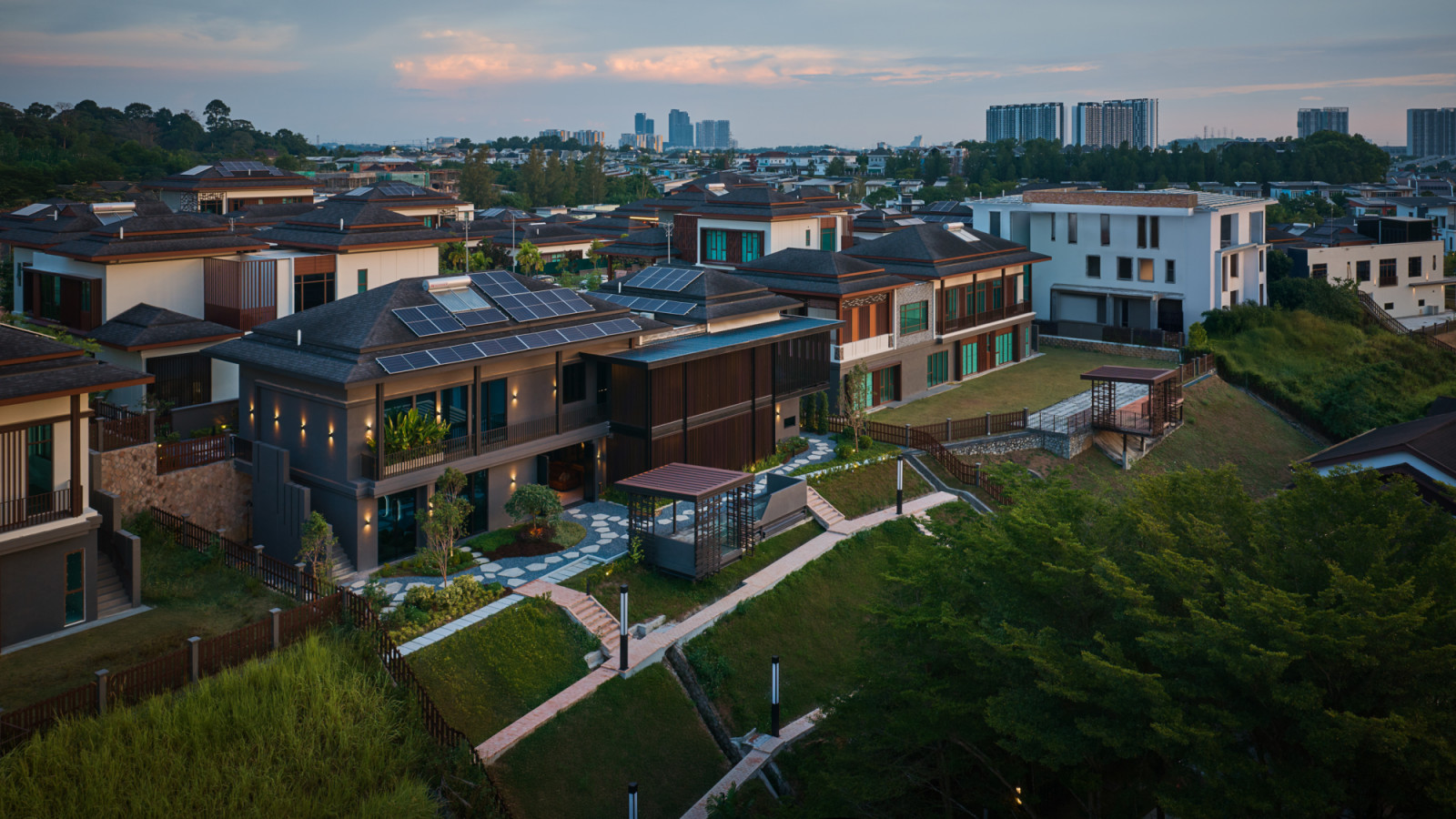 An aerial dusk photograph taken from a greater distance places House 37 against the Selangor skyline, with garden lighting visible across the terraced grounds