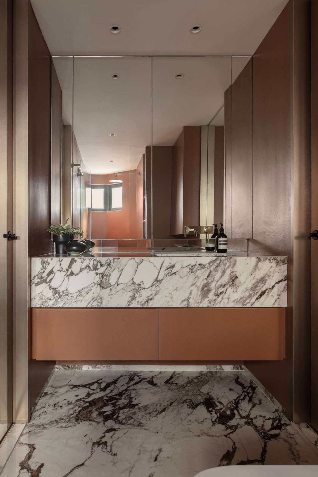 The master bath introduces a bold shift in mood, with soft vermillion microcement walls bringing in warmth