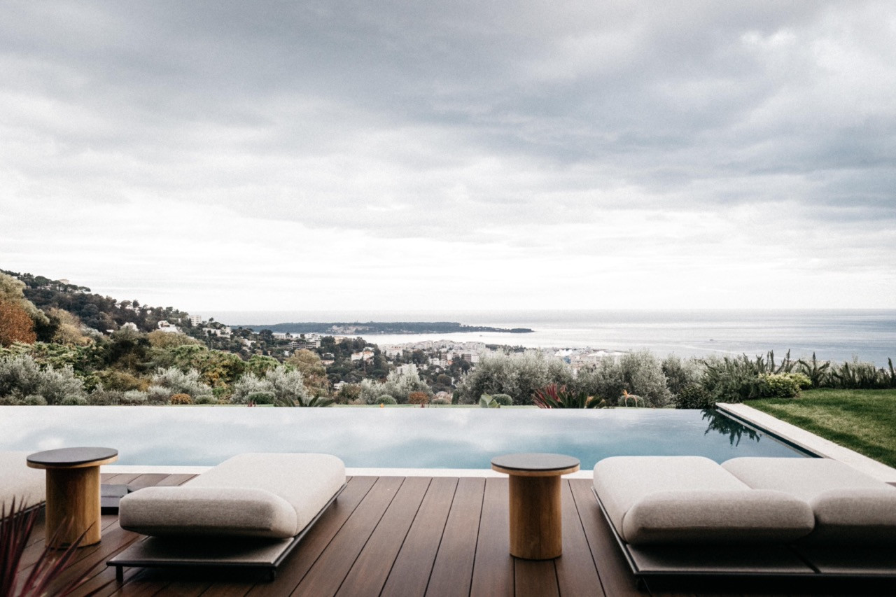 The infinity pool with two upholstered sun loungers on a teak deck, with panoramic views over Cannes and the Mediterranean