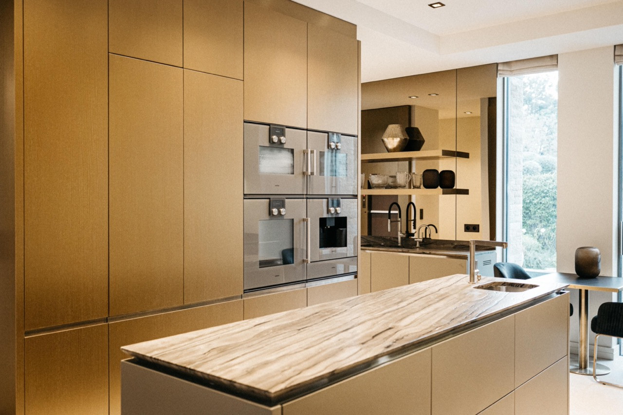 The kitchen with a marble island, floor-to-ceiling brushed brass cabinetry and integrated Gaggenau oven column