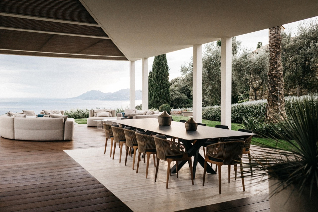 The covered outdoor terrace with a long dining table seating twelve, rope-back chairs and views over the Mediterranean