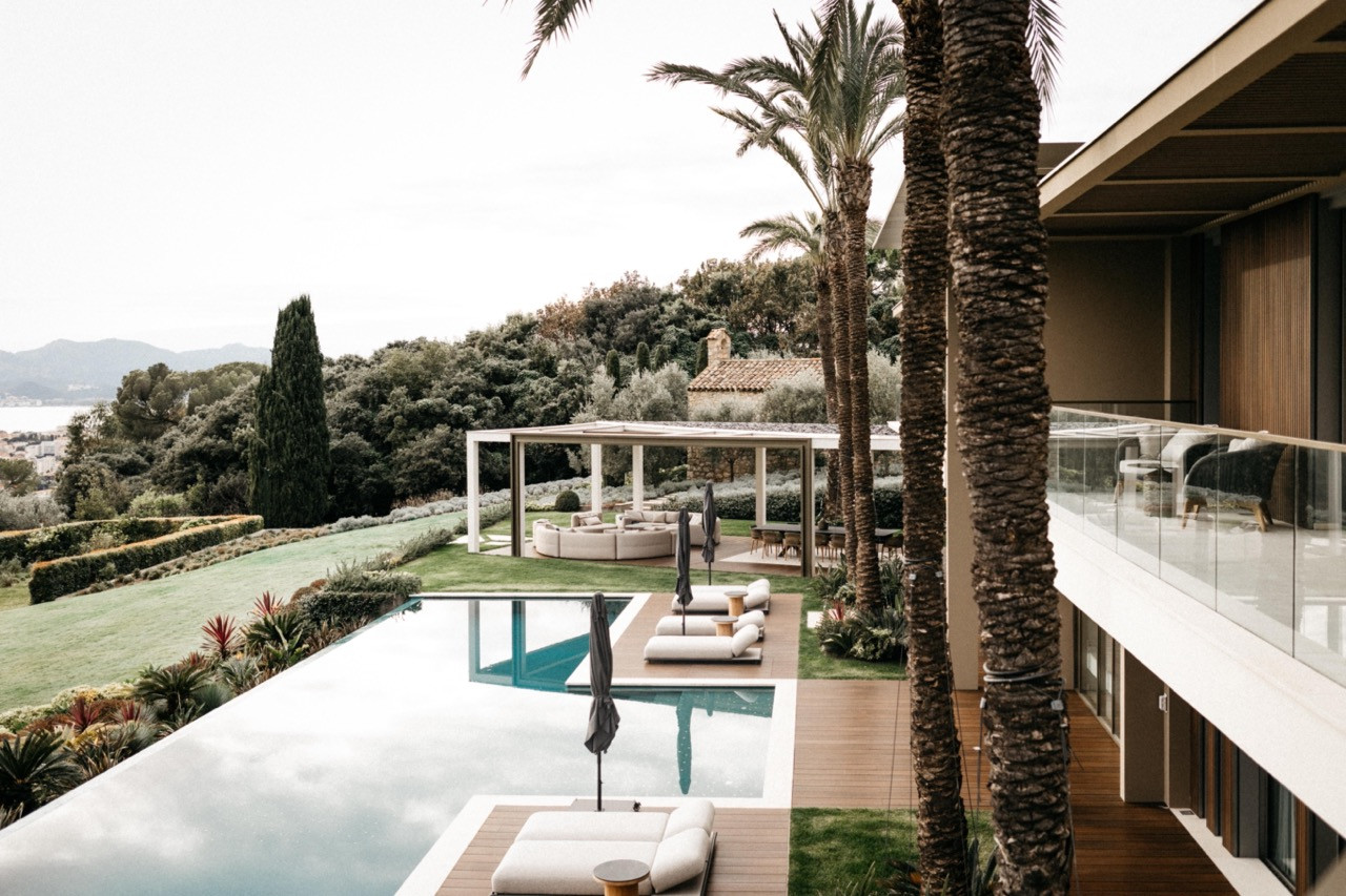 The outdoor swimming pool and terrace with sun loungers, a covered outdoor seating pavilion and views over Cannes towards the sea