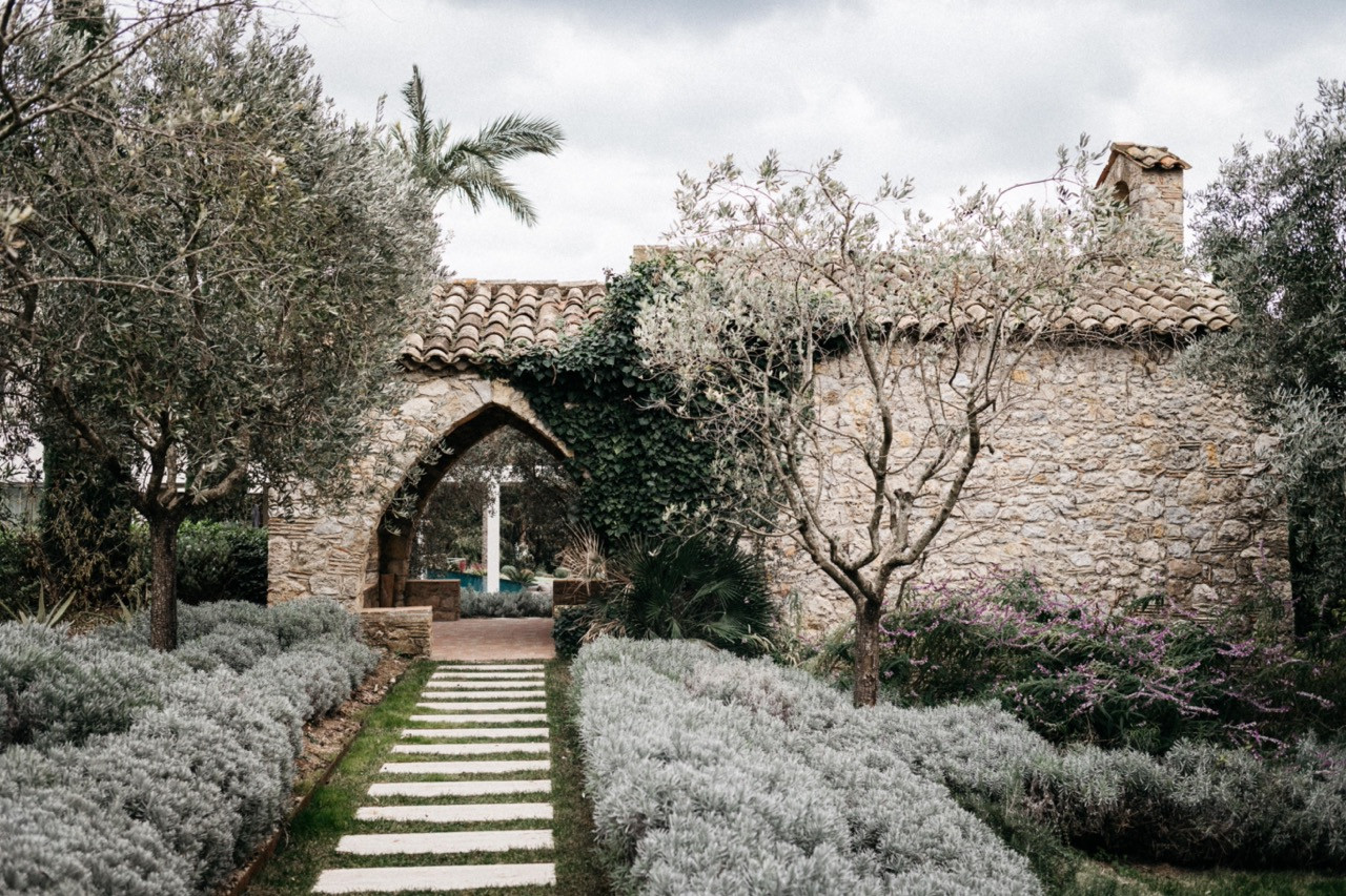 The garden path to the restored stone chapel, flanked by lavender hedging, olive trees and ivy-covered stone walls