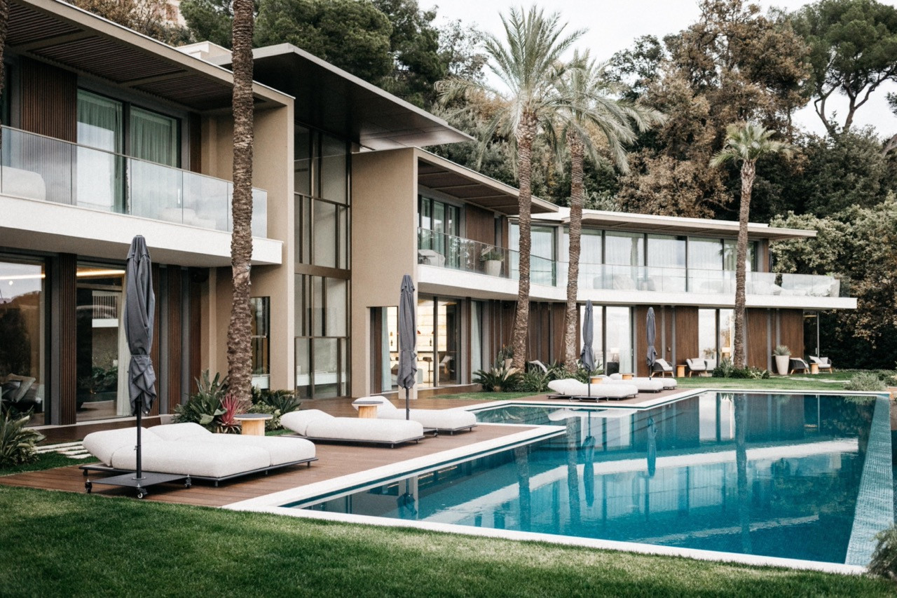The garden pavilion with a louvred roof, stone steps leading up from the lawn through layered Mediterranean planting to the covered terrace