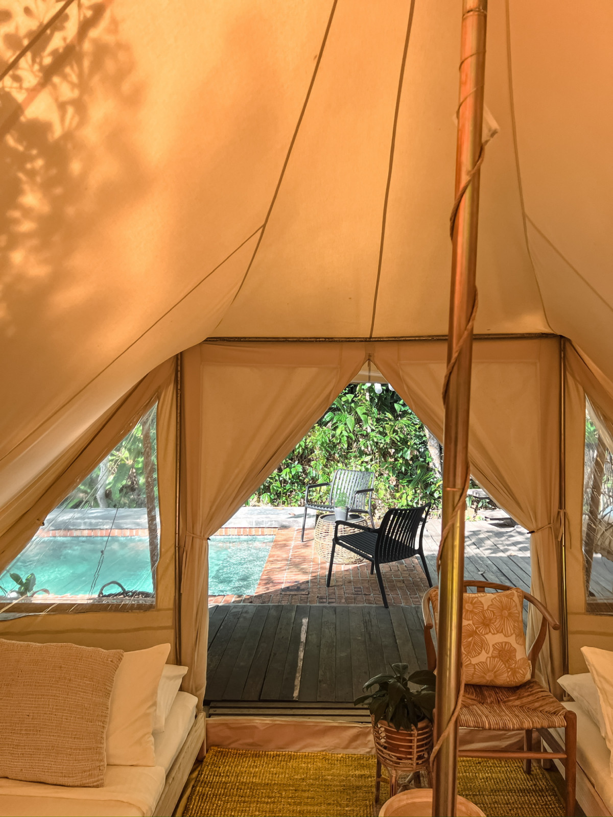 The interior of the third tent looking out through the open entrance toward the pool and timber deck beyond