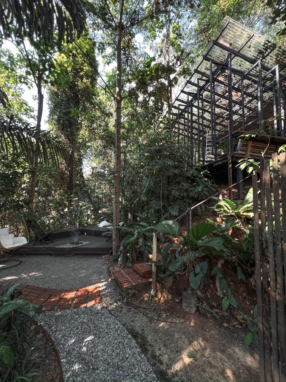 The gravel and brick pathway connecting the terraced levels of the La Hilir site, with the steel-framed pavilion visible above