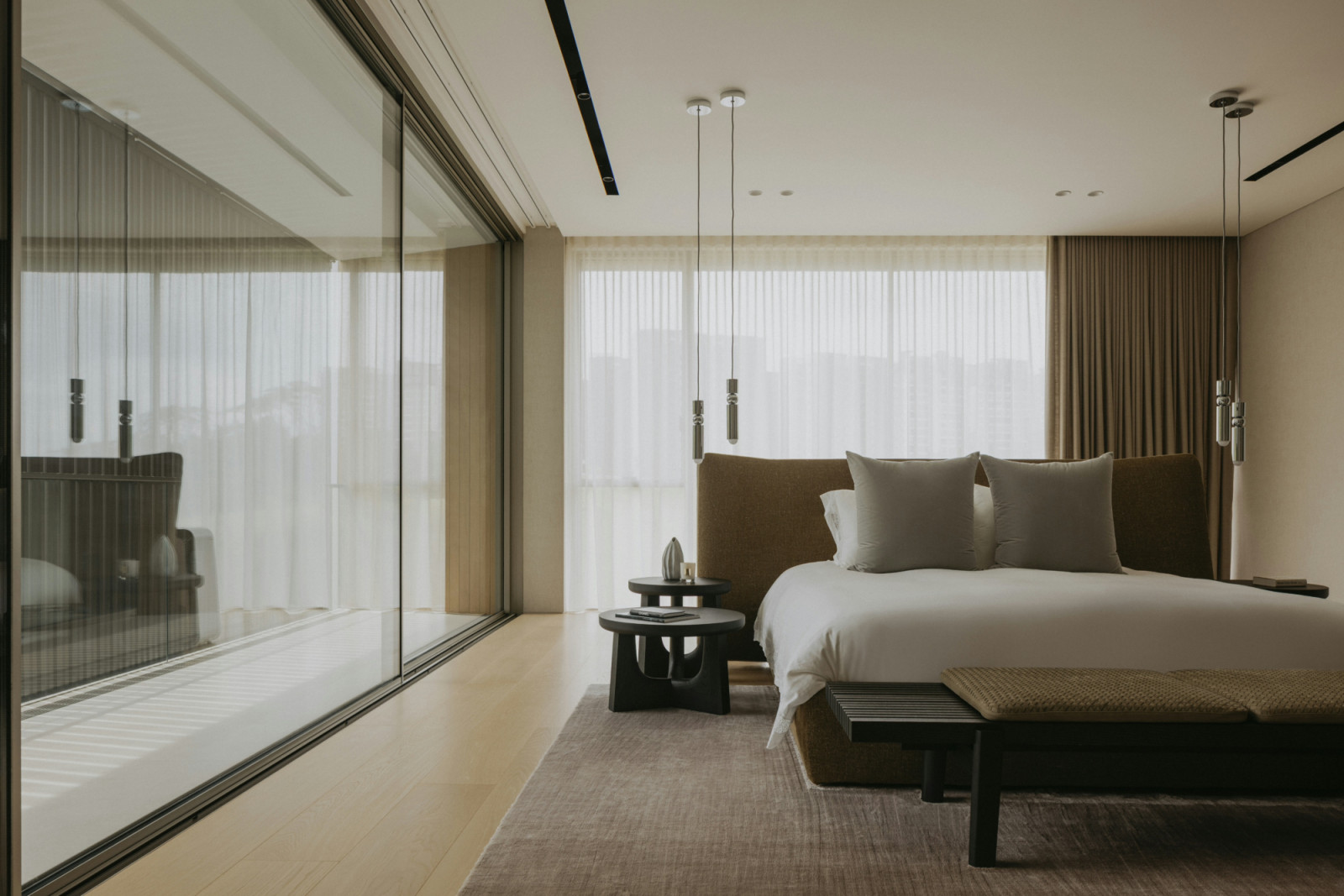 Clear sliding doors and expansive windows saturate this bedroom with light and airiness
