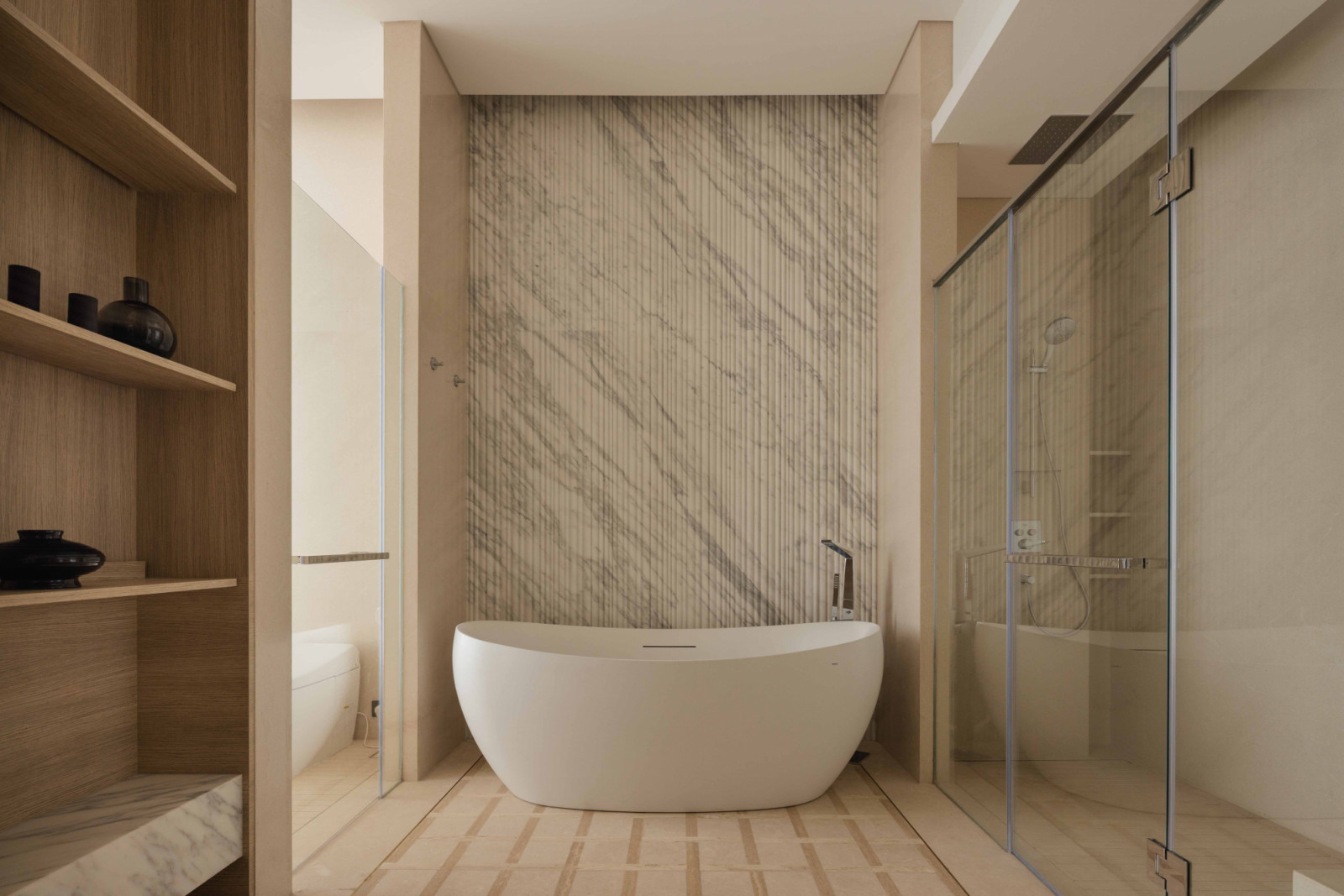 A freestanding Toto bathtub sits against a CNC-fluted statuario marble wall in the master bathroom