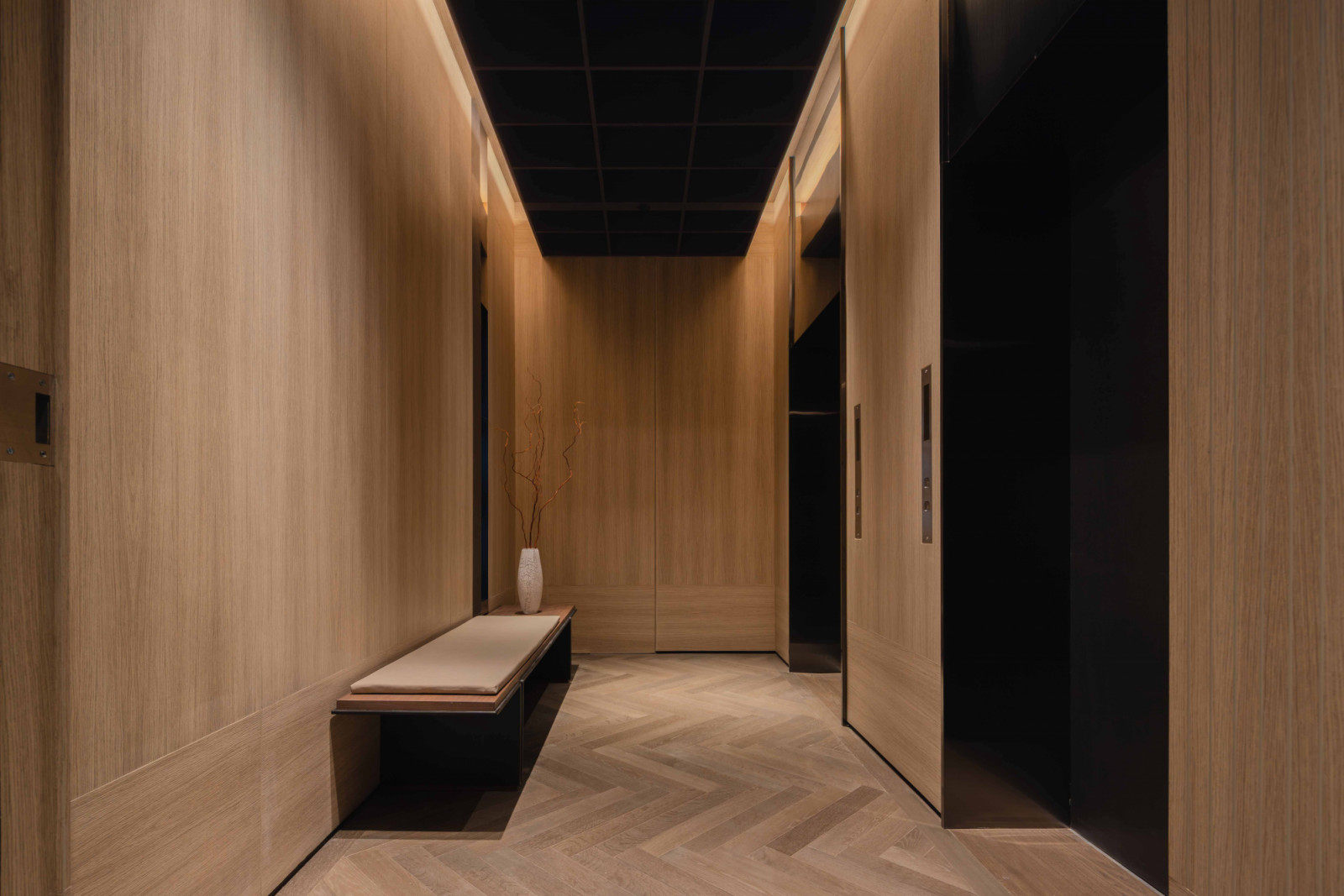 The private lift lobby is clad in dark timber ceiling and warm oak panelling to create an intimate arrival experience