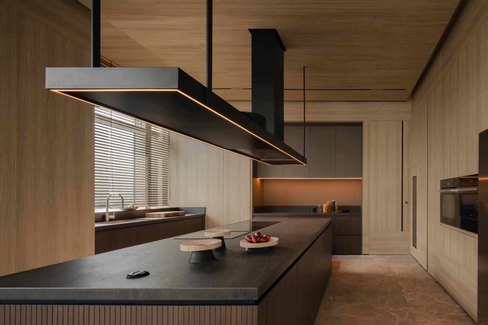 The dry kitchen features a large Dekton island and dramatic pendant hood, designed for serious cooking.