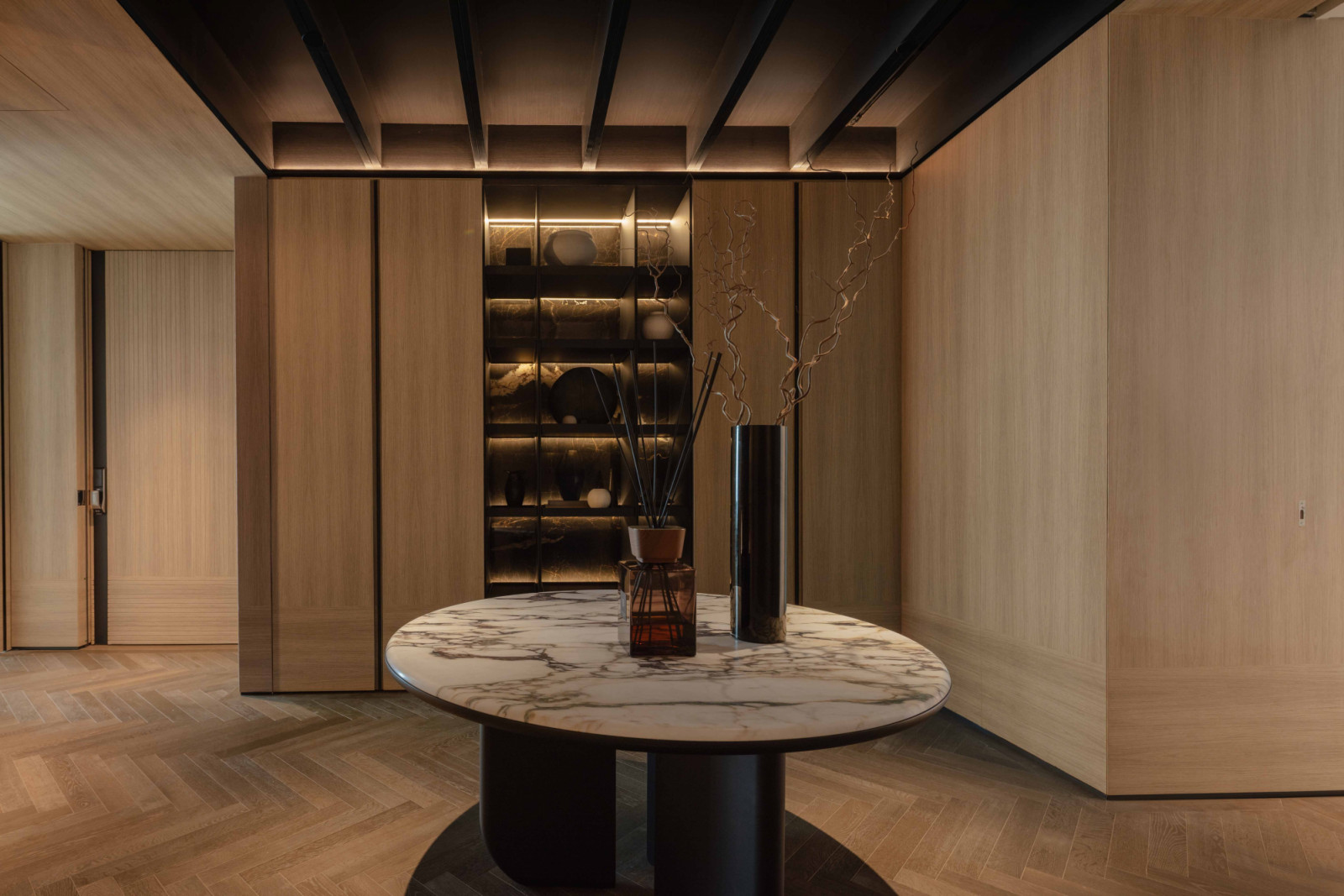 A marble-topped table and backlit display shelving anchor the entrance foyer