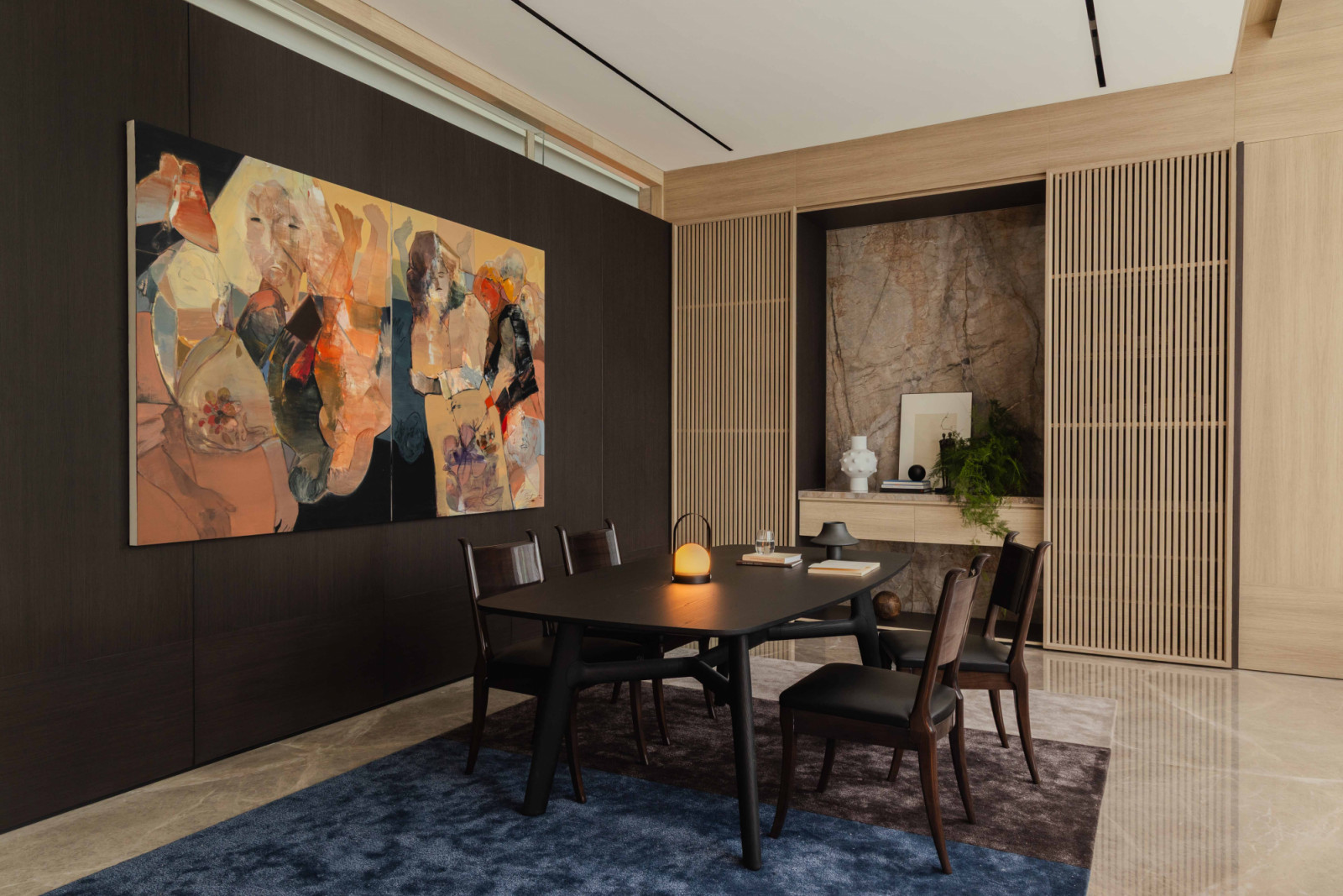 A painting by Indonesian artist Eric Pradana hangs above the Poliform study table, paired with a Christian Liaigre chair and a blue Moire Rugs carpet