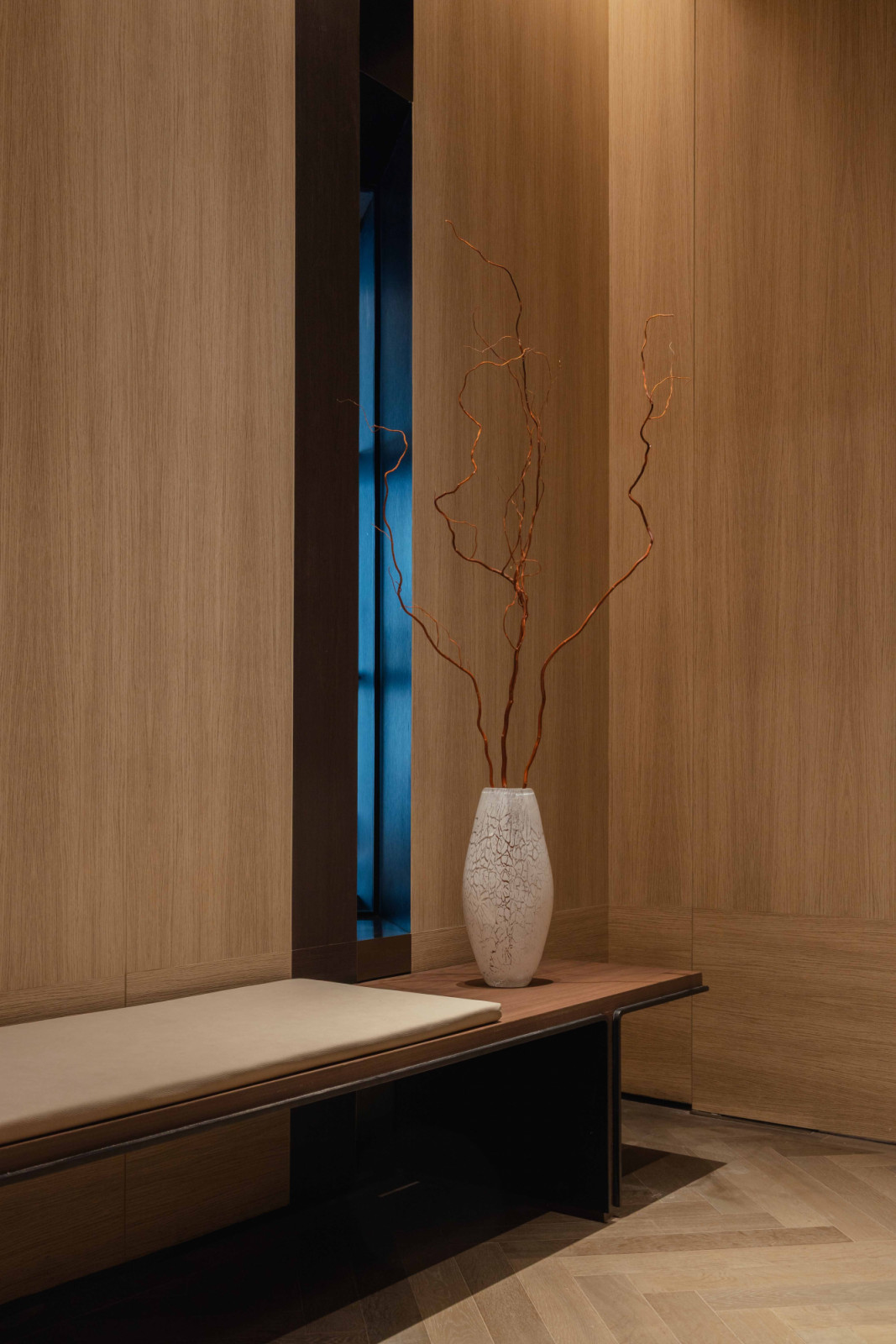 The city skyline glimpsed through the lift lobby window hints at the panoramic views beyond