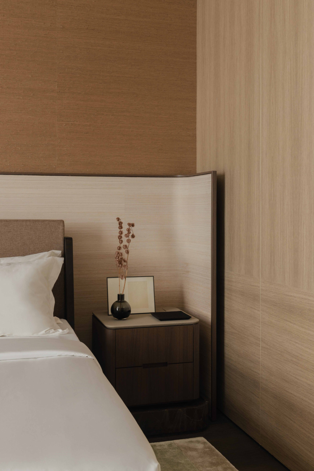 The Christian Liaigre bed is paired with a bespoke bedside table and grasscloth wall covering