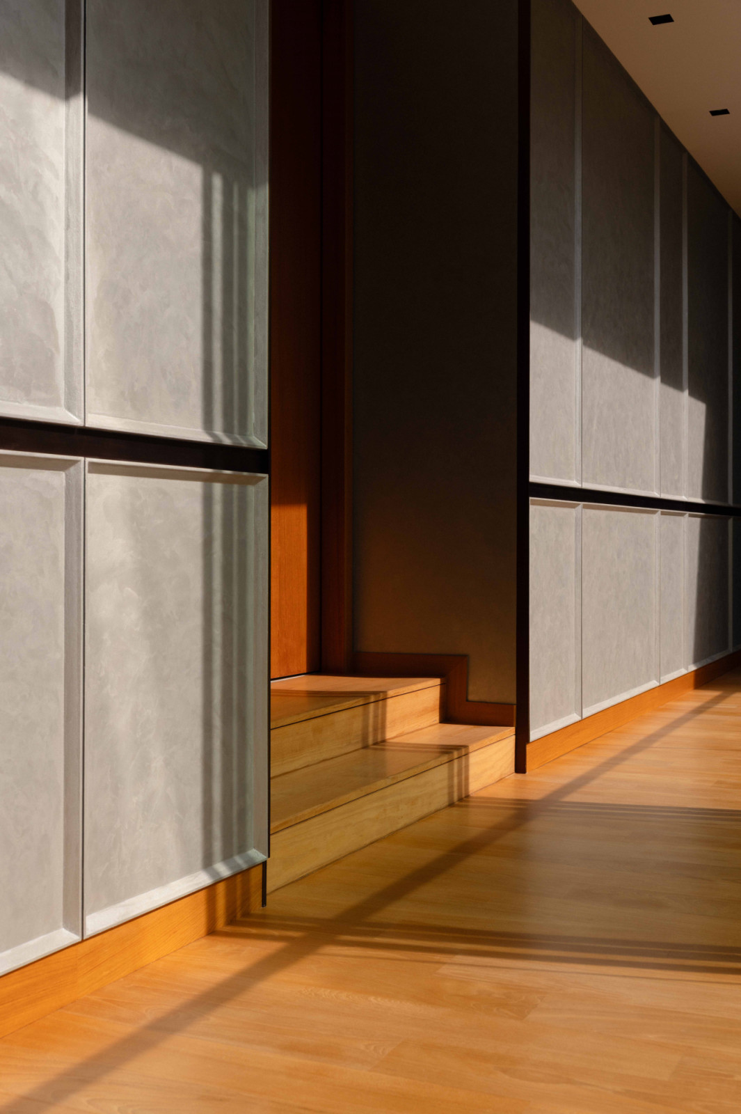 One of four corridor treatments where shafts of natural light cast dramatic shadow play across the considered wall panelling.