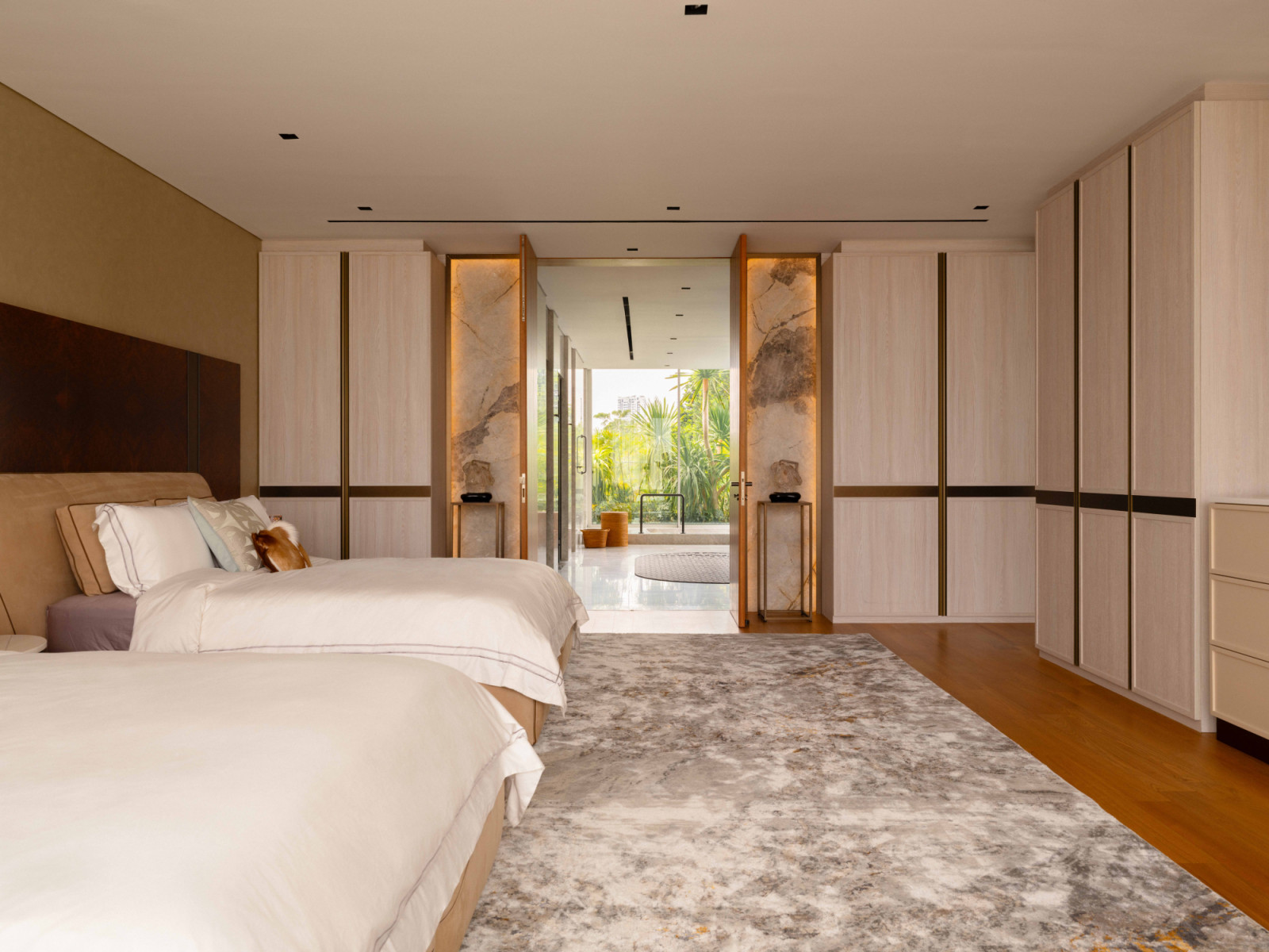 The bedroom opens through a pair of illuminated marble-flanked doors to the pool terrace