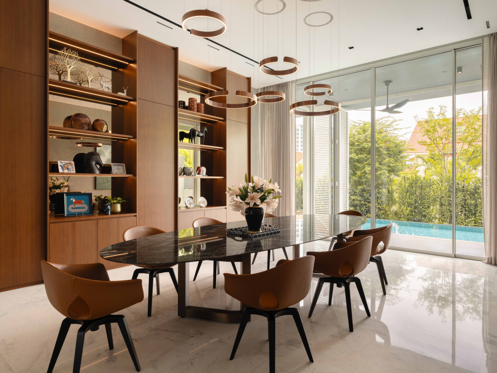 The dry kitchen’s dining area opens directly to the pool, with bespoke display cabinetry and circular pendant lights overhead