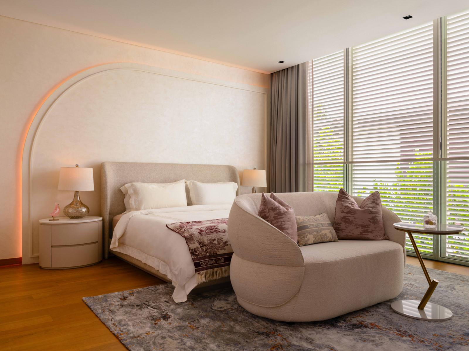 The daughter’s bedroom wraps its soft-arched headboard wall in warm blush tones, with a curved sofa and Dior toile accents completing the feminine palette